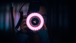 Fotograaf met camera uitgerust met ringflitser, gebruikt bij flitsfotografie in donkere omgeving
