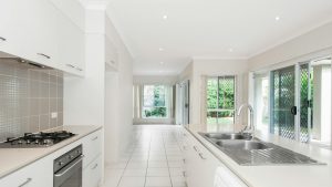 Heldere keuken met witte kasten, gasfornuis en zicht op tuin, perfect vastgelegd voor sterke verkoopfoto’s woning