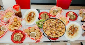 Tafel vol dinerrestaurantgerechten zoals pizza, kip, pasta en friet, geserveerd in Amerikaanse stijl